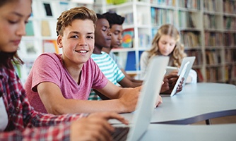 a smiling teen sitting in a library