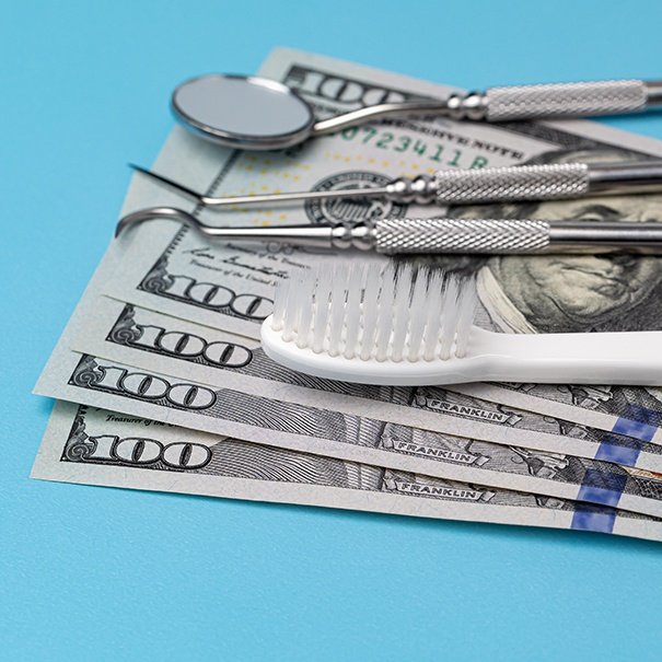 stack of money with dental instruments